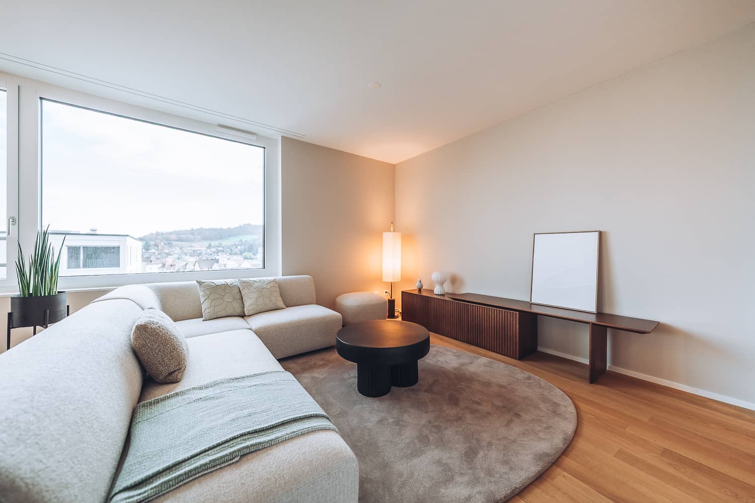 Ein grosses Ecksofa steht im Wohnzimmer mitsamt Teppich, Couchtisch und Sideboard